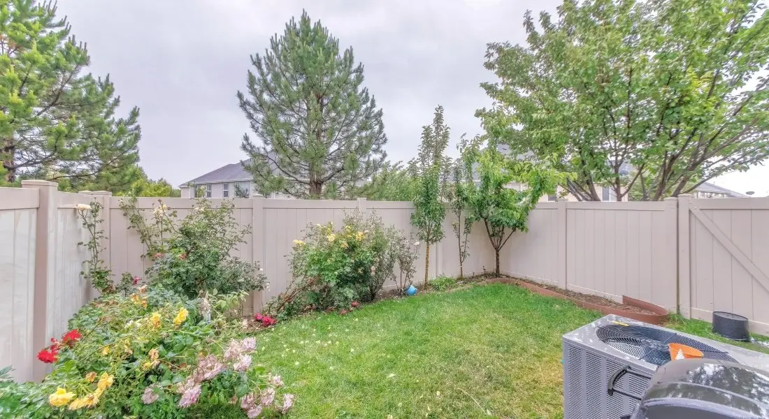 beige vinyl privacy fence enclosing a small backyard garden