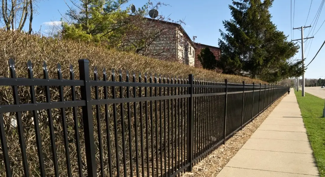 black metal fence with spear top design along a sidewalk