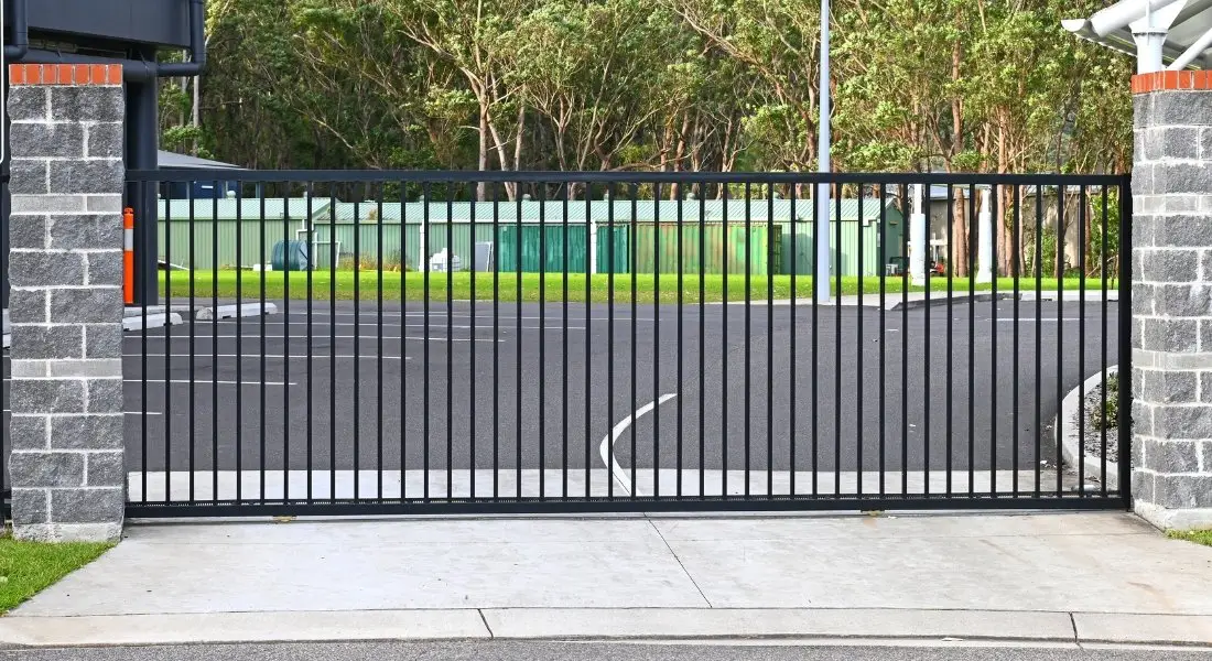 black sliding metal gate with stone pillars