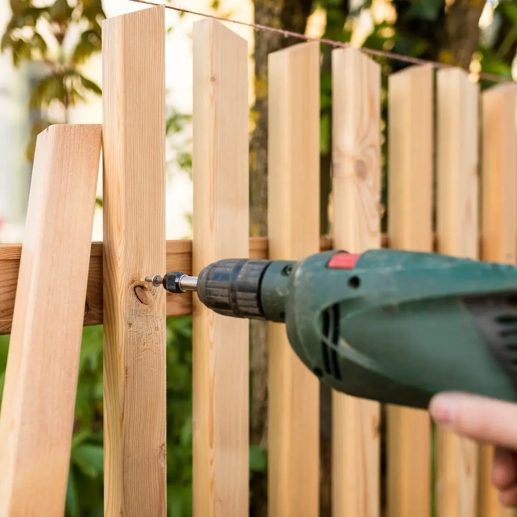 close up of a drill fastening wooden fence boards