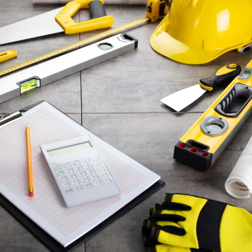 construction tools, hard hat, and calculator on a work surface