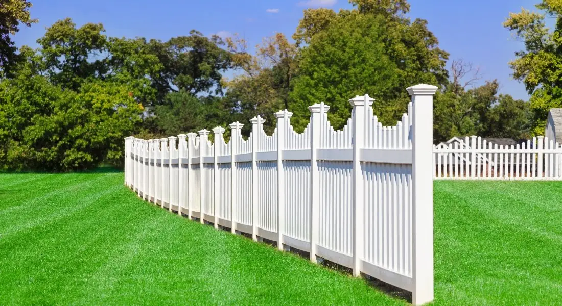 decorative white vinyl fence with scalloped design in large yard
