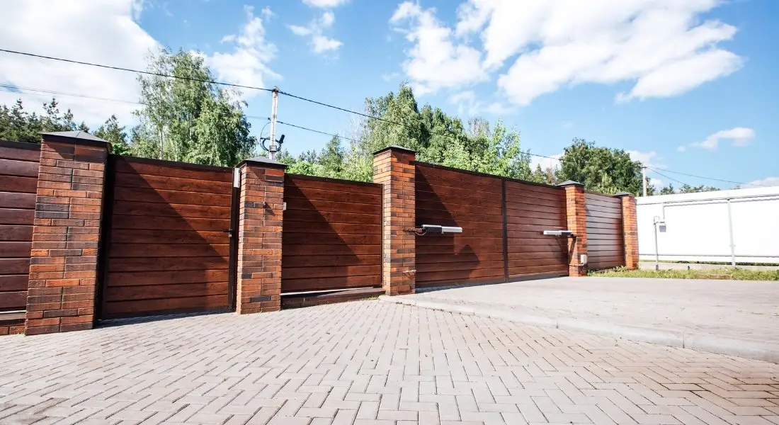 large wooden driveway gate with brick pillars