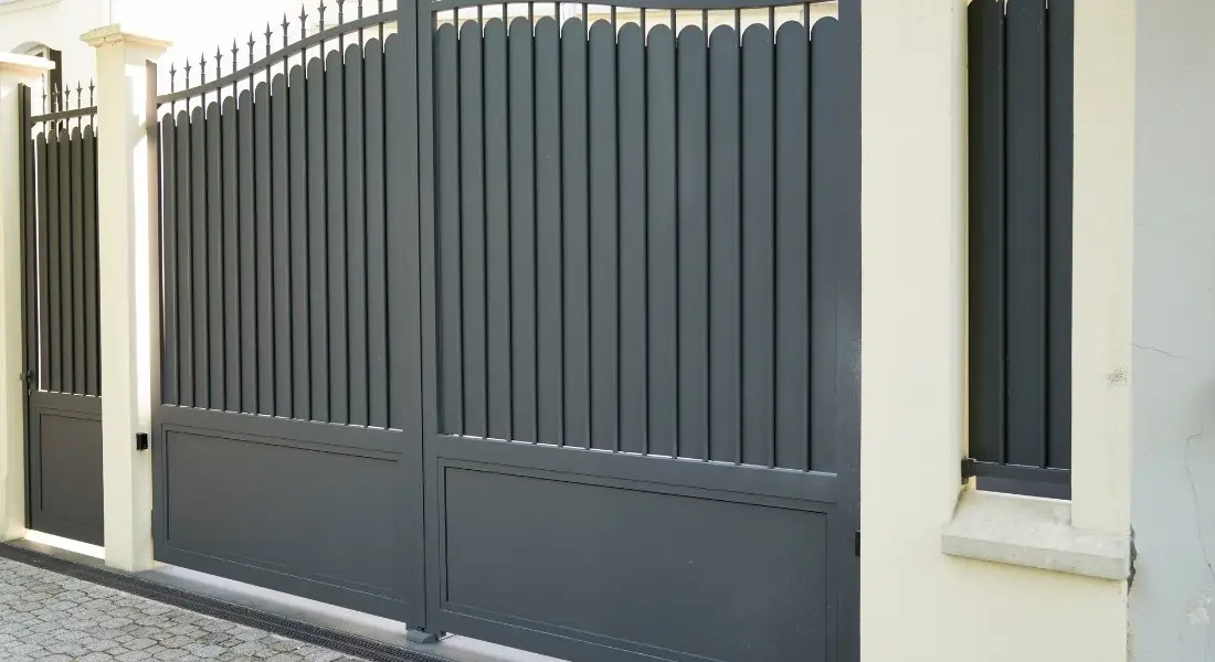tall gray metal gate with vertical slats and decorative top