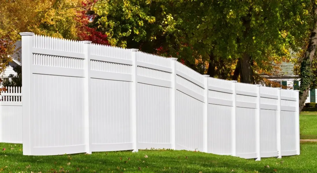 tall white vinyl privacy fence with decorative lattice top in backyard