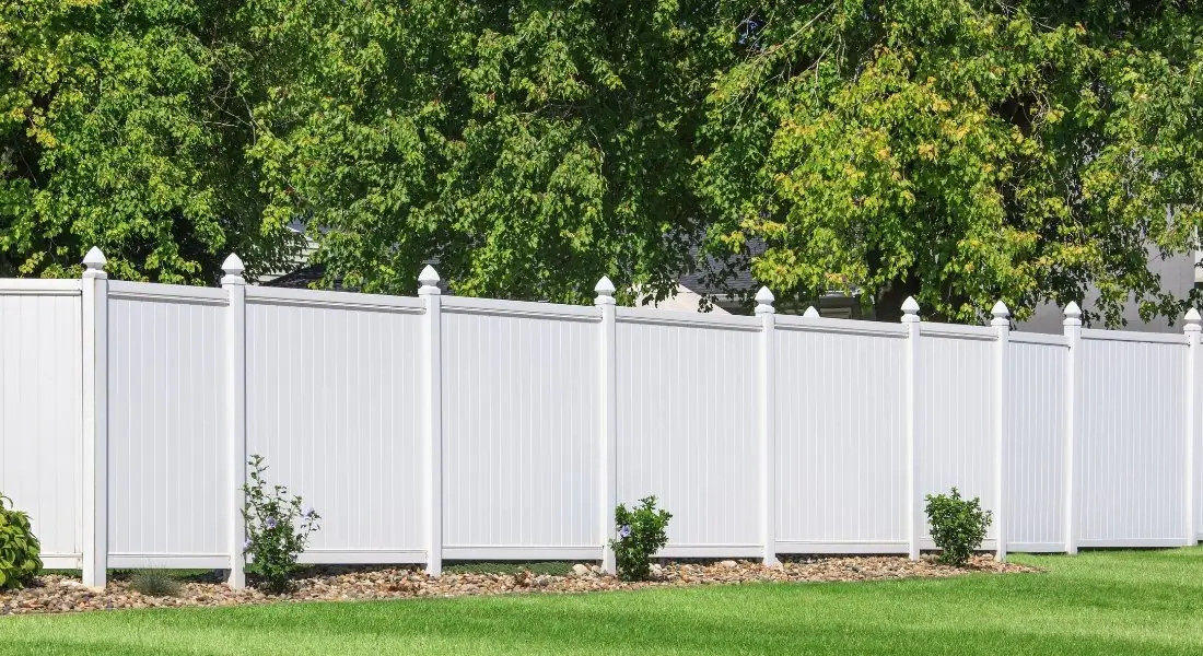 tall white vinyl privacy fence with decorative posts in backyard
