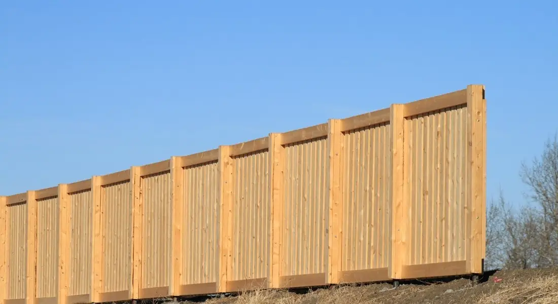 tall wood privacy fence with vertical boards under blue sky