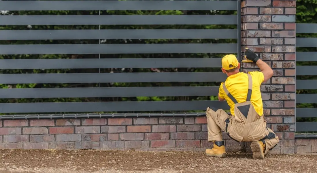 worker installing a modern brick and metal fence